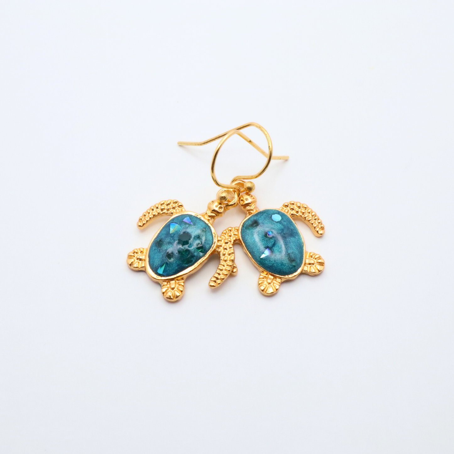Turtle-shaped earrings with teal blue resin on a white background