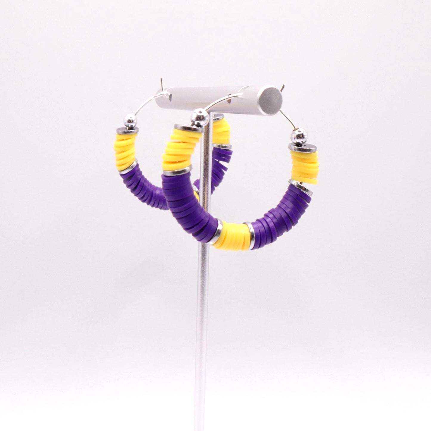 Purple and gold heishi bead hoop earrings with gold accents displayed on a branded card against a clean white background