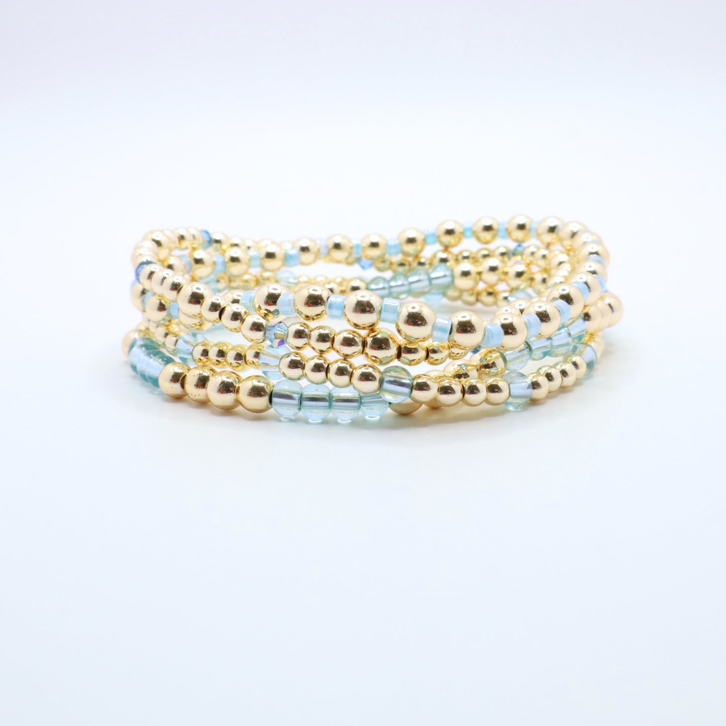 Stretch bracelet stack in soft blue and gold tones designed for layering.