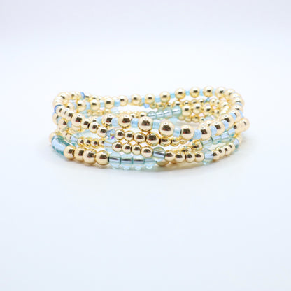 Stretch bracelet stack in soft blue and gold tones designed for layering.