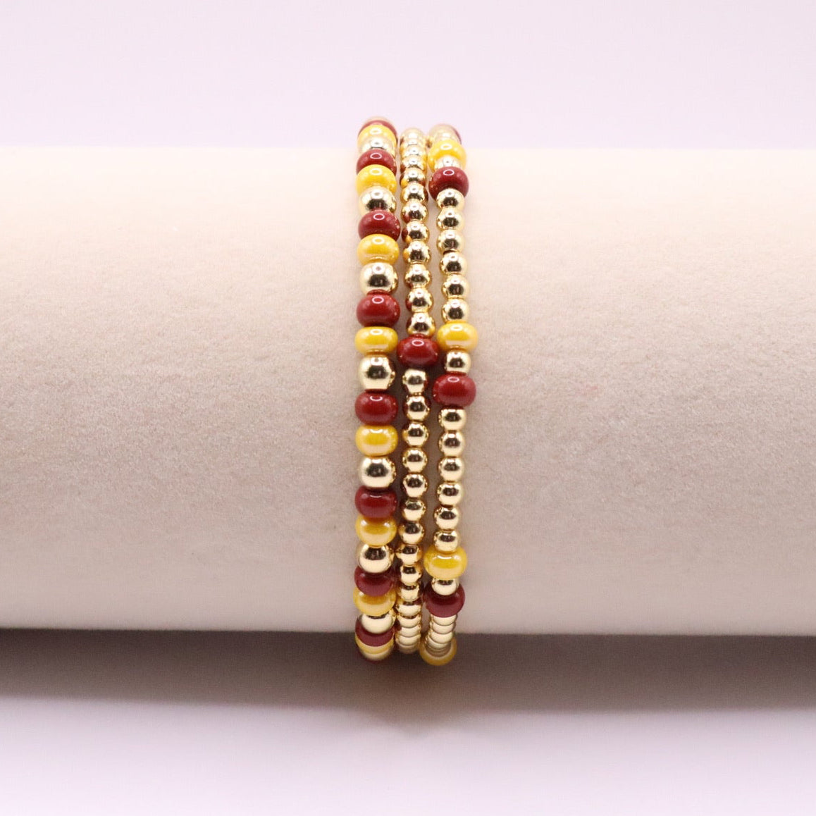 Three burgundy and gold bracelets on a display
