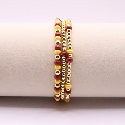 Three burgundy and gold bracelets on a display
