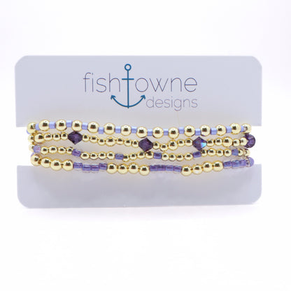 Handmade Lavender Tides bracelet stack featuring gold-tone beads, lavender seed beads, and purple crystal accents displayed on a jewelry card.