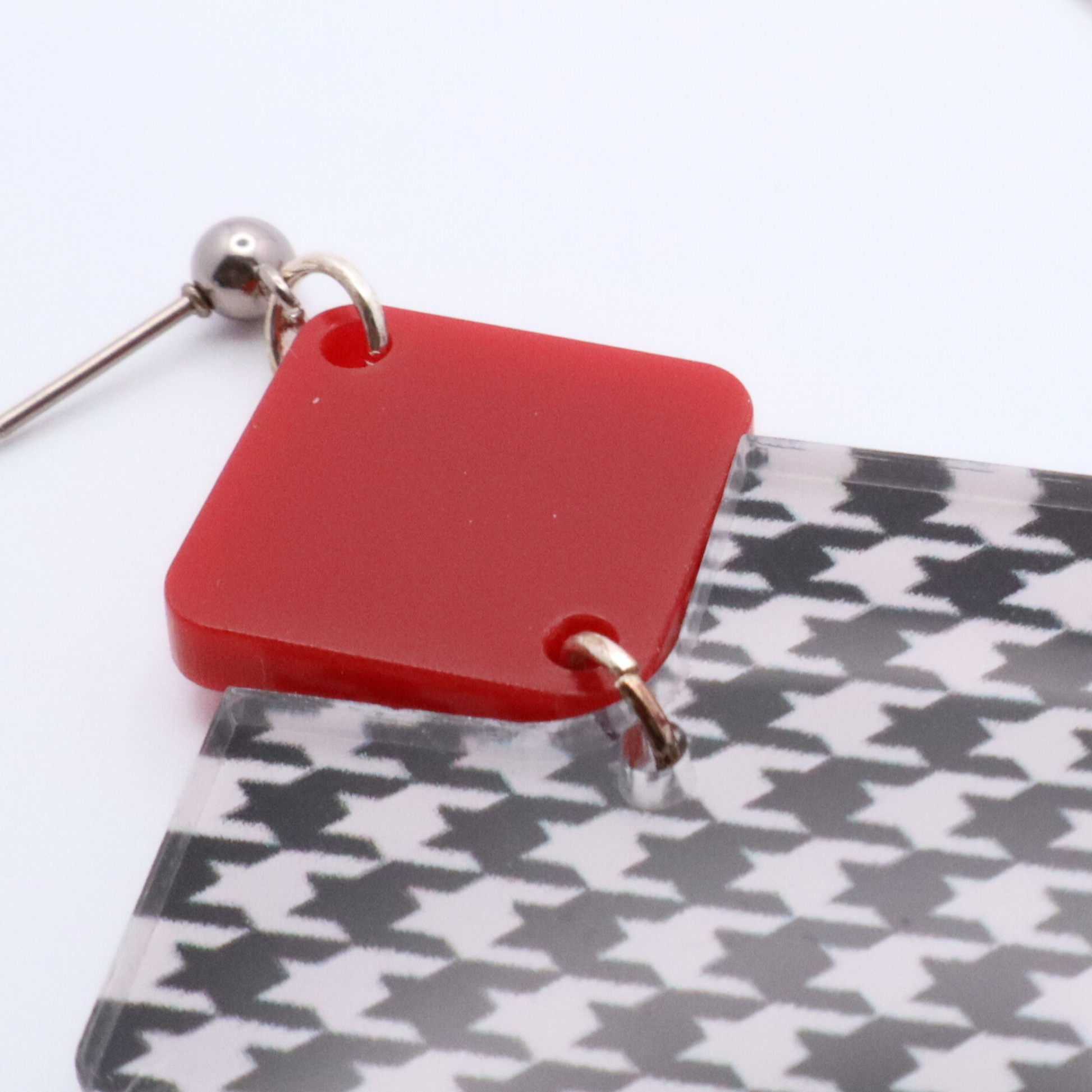 Earring with red square and houndstooth pattern on a white background