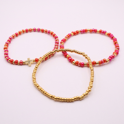 Three beaded bracelets with pink and gold beads on a light pink background