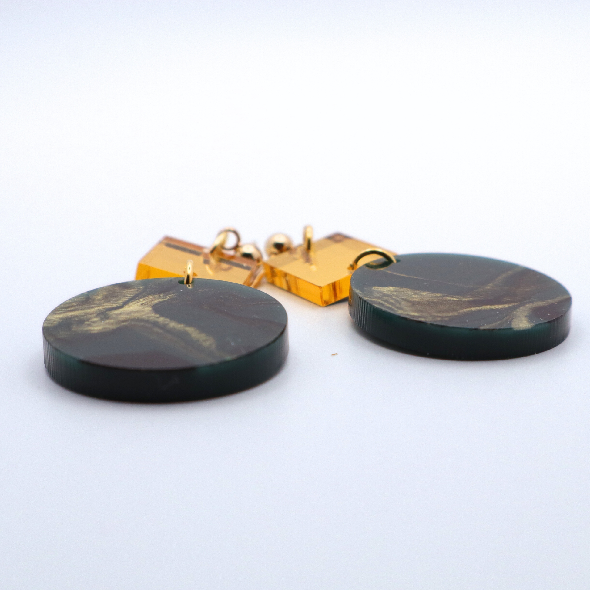 Green and gold marbled earrings on a white background