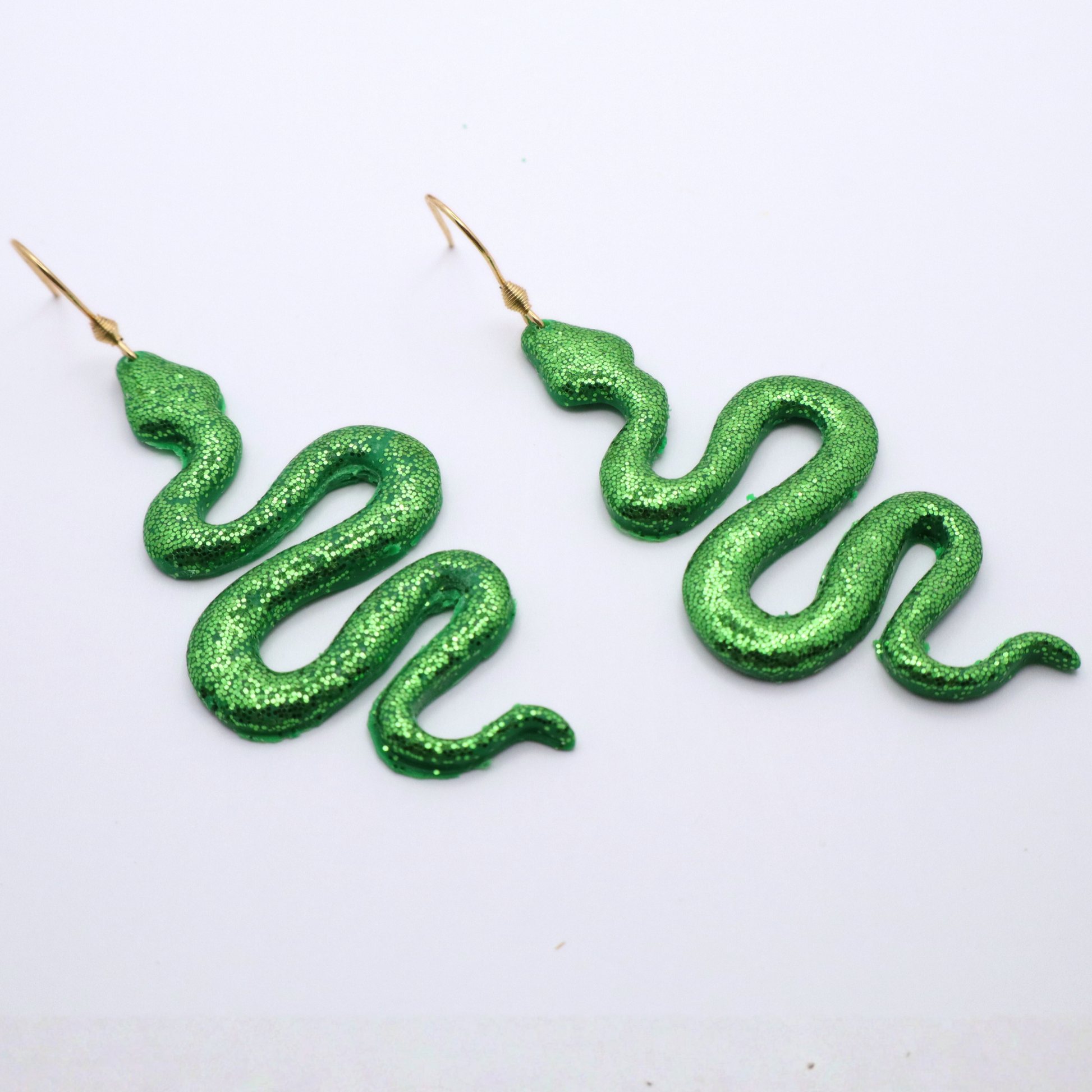 Green snake-shaped earrings on a white background