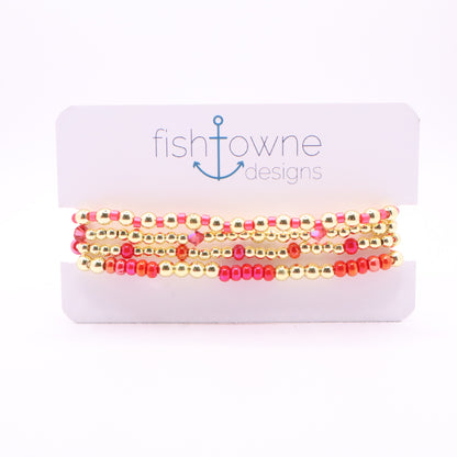 Four-piece pink and coral bracelet stack with gold hematite beads and crystal accents.