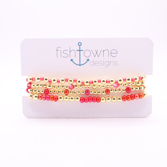 Four-piece pink and coral bracelet stack with gold hematite beads and crystal accents.