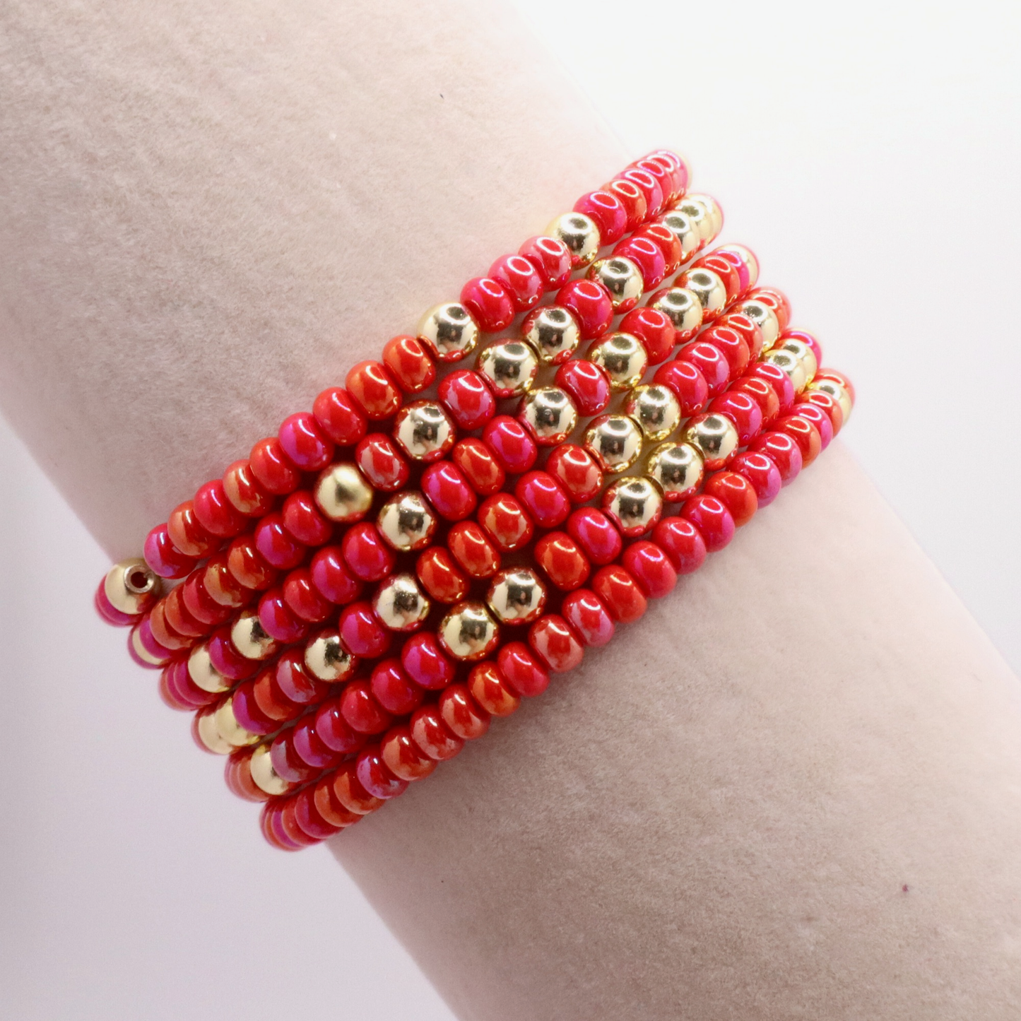 Stack of six pink and gold beaded bracelets on a jewelry display.
