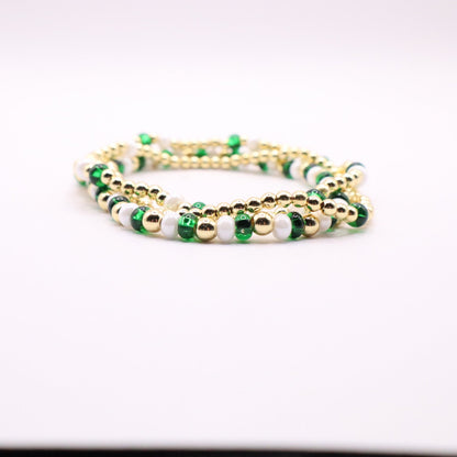 Three green, white, and gold bracelets on a light background.