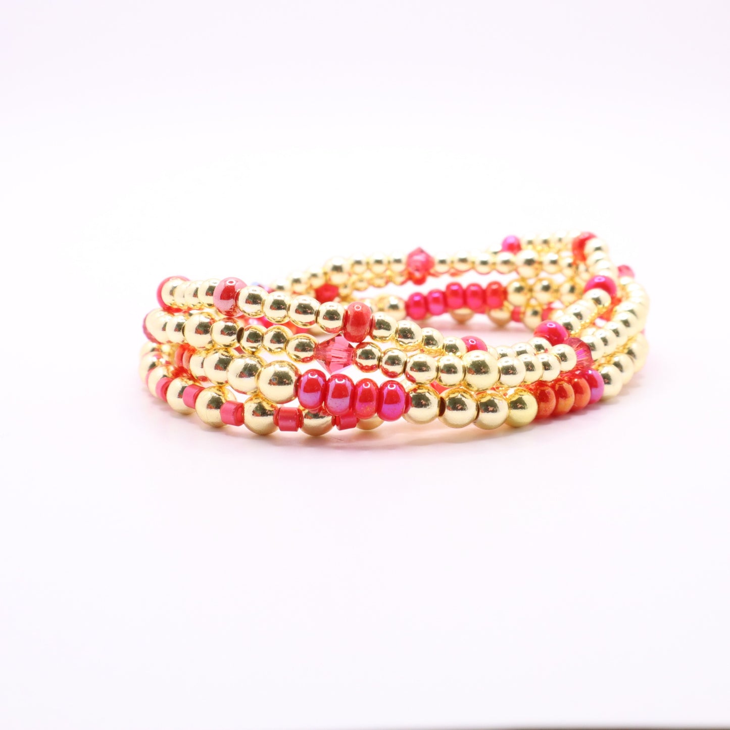 Handmade bracelet set featuring bright pink, coral, and gold beaded stretch bracelets.