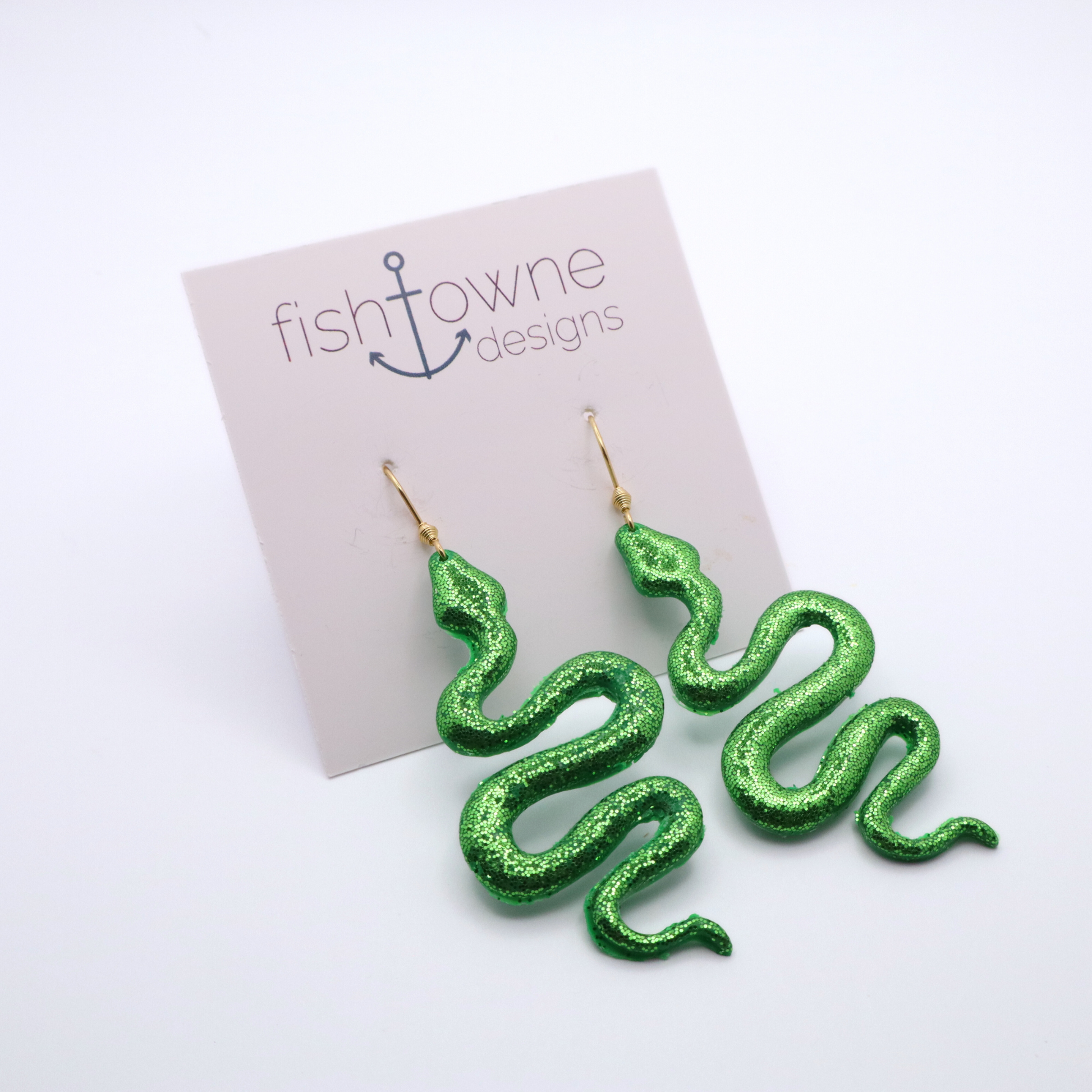Green glitter snake-shaped earrings on a Fish Towne Designs card.