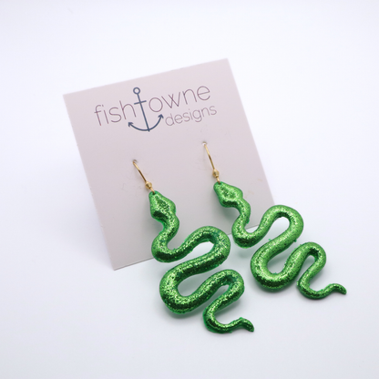 Green glitter snake-shaped earrings on a Fish Towne Designs card.