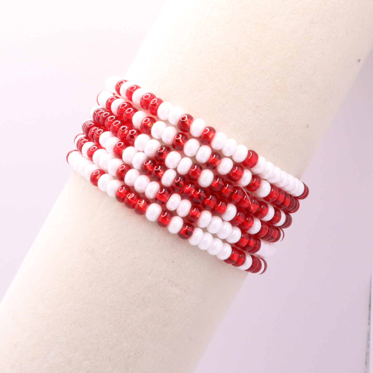 Set of six red and white seed bead stretch bracelets featuring random red and white seed beads on a white background