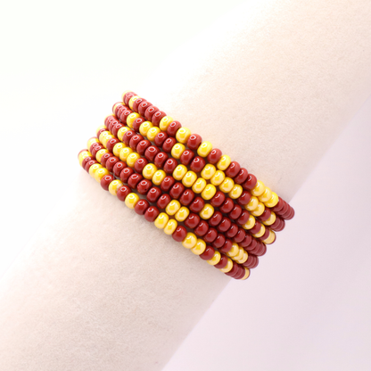 Set of six burgundy and gold seed bead stretch bracelets featuring random burgundy and gold seed beads on a white background