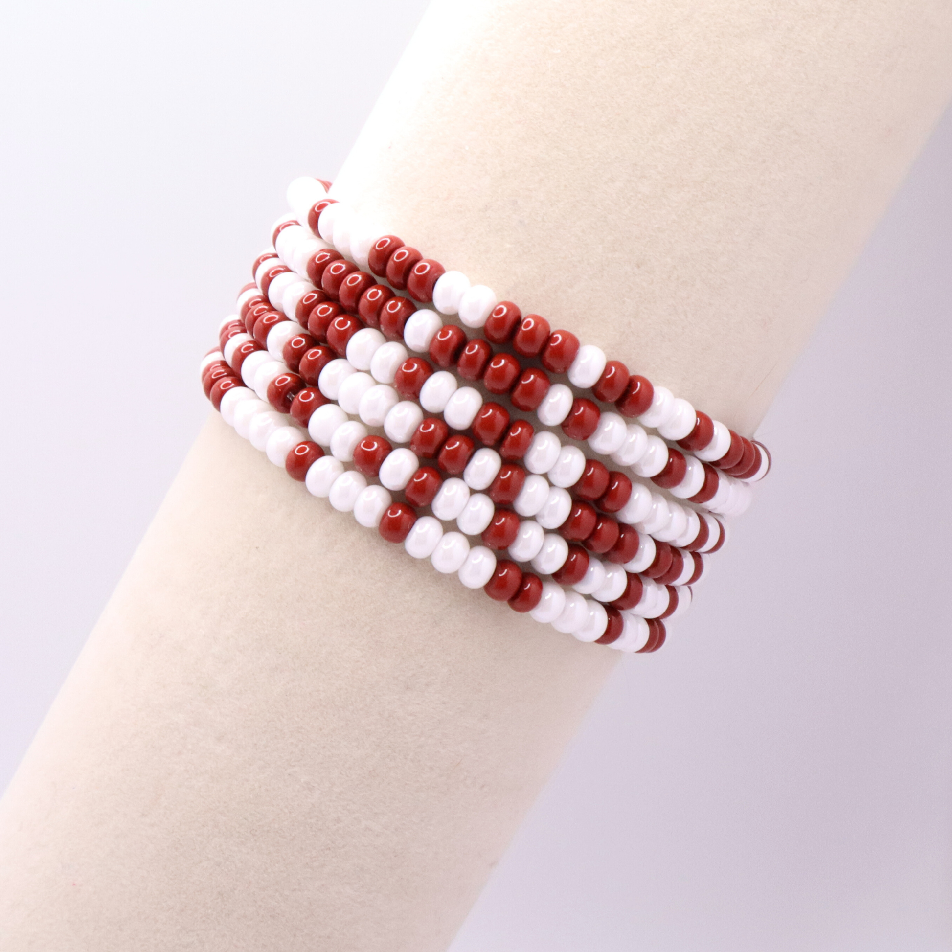 Set of six crimson and white seed bead stretch bracelets featuring random crimson and white seed beads on a white background