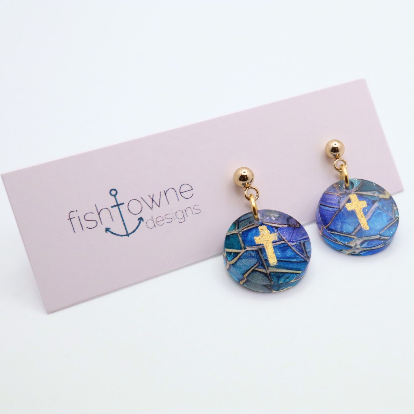 Blue acrylic dangle earrings with gold cross design and stained glass pattern on stainless steel stud posts