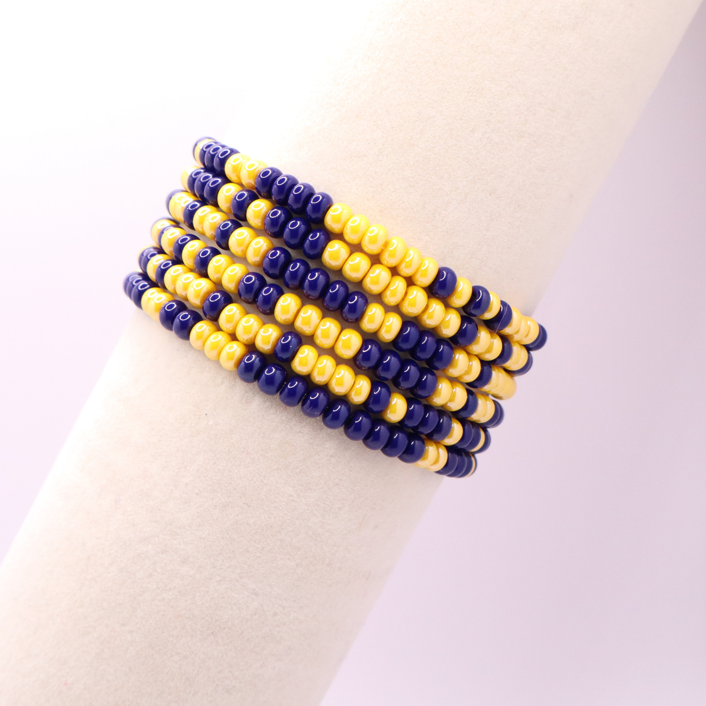 Set of six navy blue and gold seed bead stretch bracelets featuring random red and white seed beads on a white background