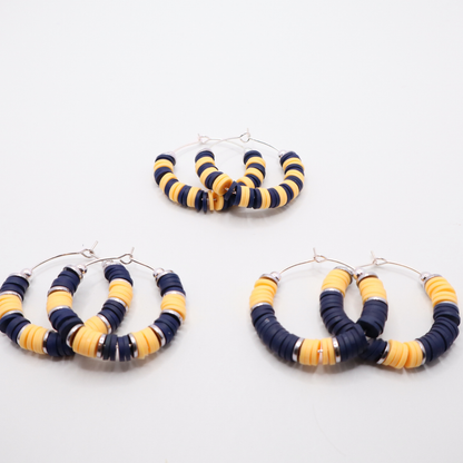 Set of three navy and gold heishi bead hoop earring styles arranged on a white background, showcasing size and pattern variations