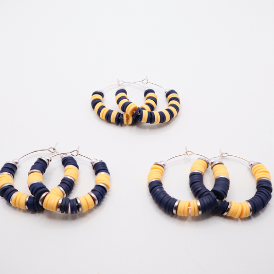 Set of three navy and gold heishi bead hoop earring styles arranged on a white background, showcasing size and pattern variations