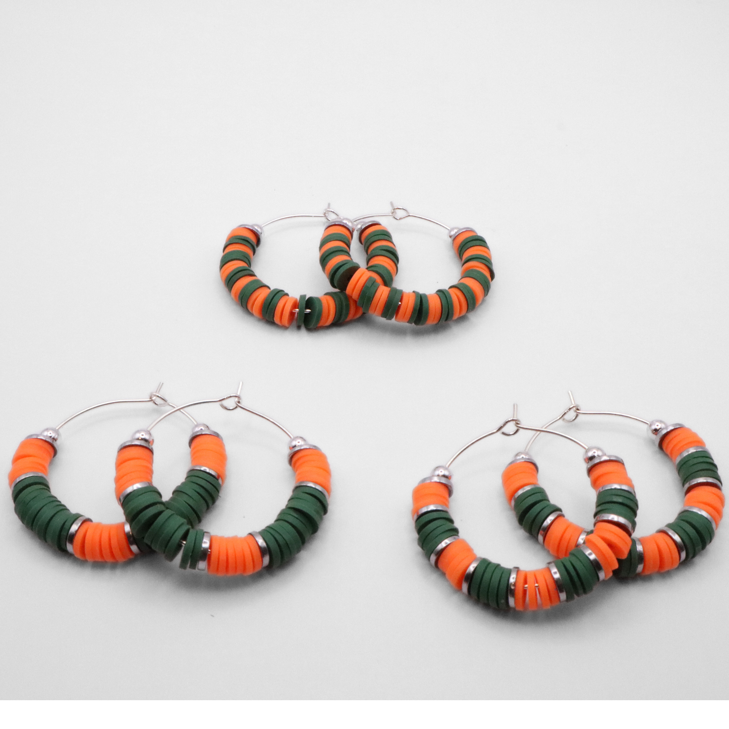 Set of three orange and green heishi bead hoop earring styles arranged on a white background, showcasing size and pattern variations