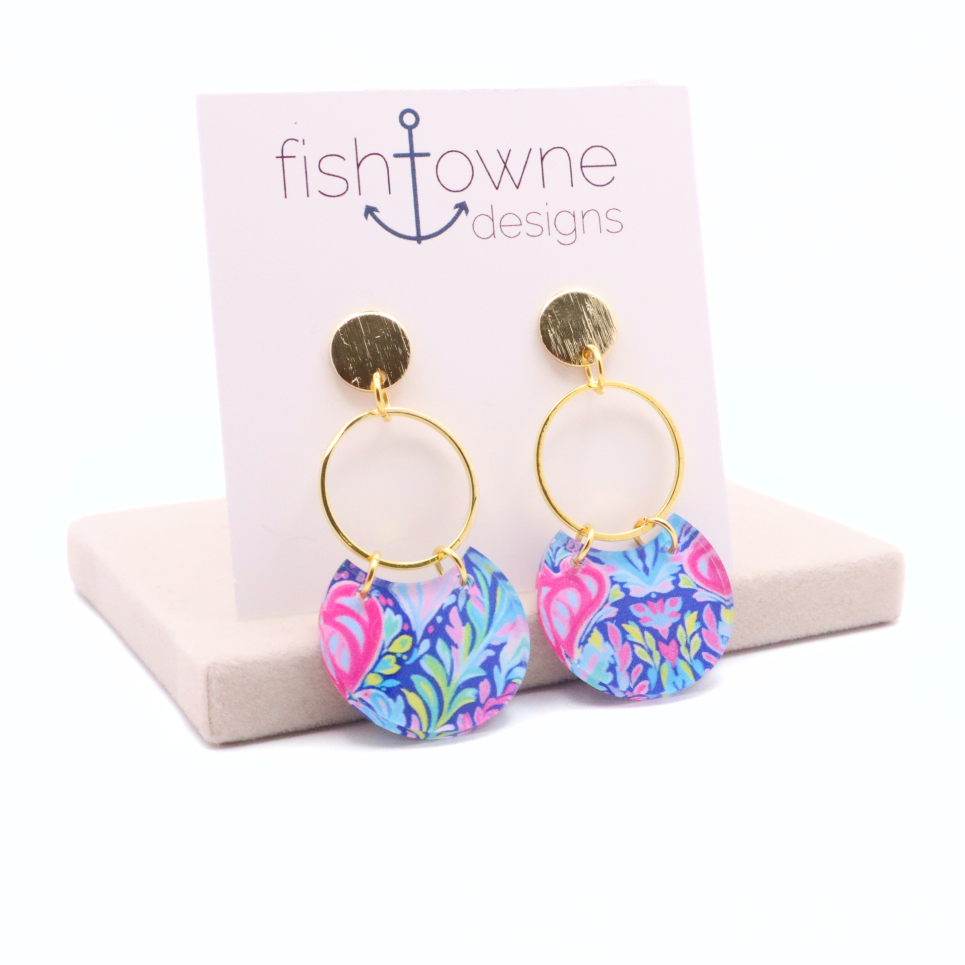 Colorful patterned acrylic earrings featuring vibrant floral and abstract design on gold hoops with 18k gold plated stud posts on display stand