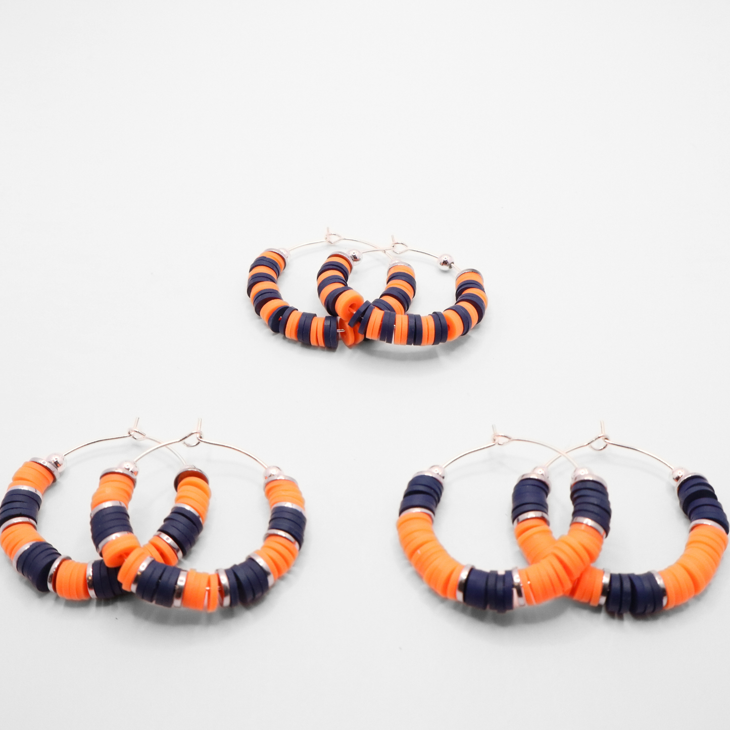 Set of three navy blue and white heishi bead hoop earring styles arranged on a white background, showcasing size and pattern variations