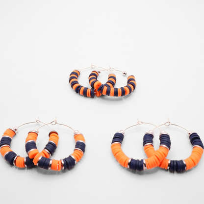 Set of three navy blue and white heishi bead hoop earring styles arranged on a white background, showcasing size and pattern variations