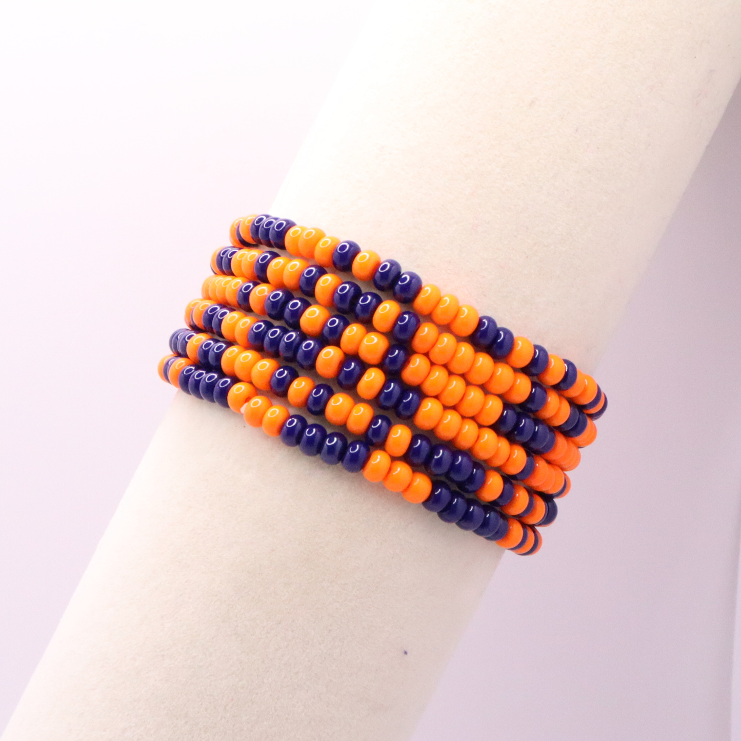 Set of six orange and navy blue seed bead stretch bracelets featuring random orange and navy blue seed beads on a white background