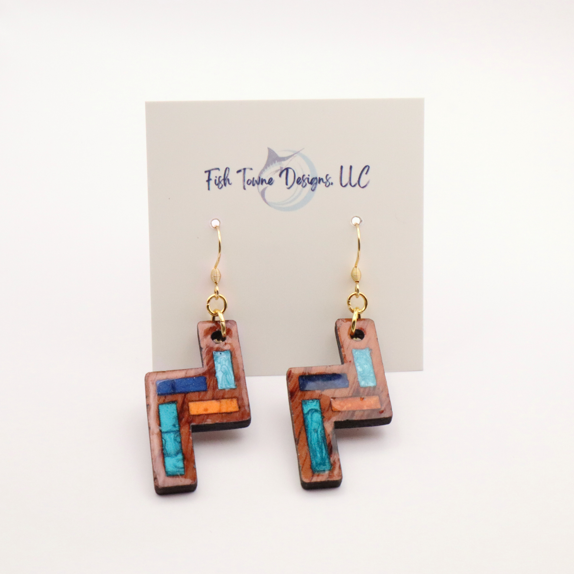 Wooden earrings with blue accents on a Fish town Designs card.