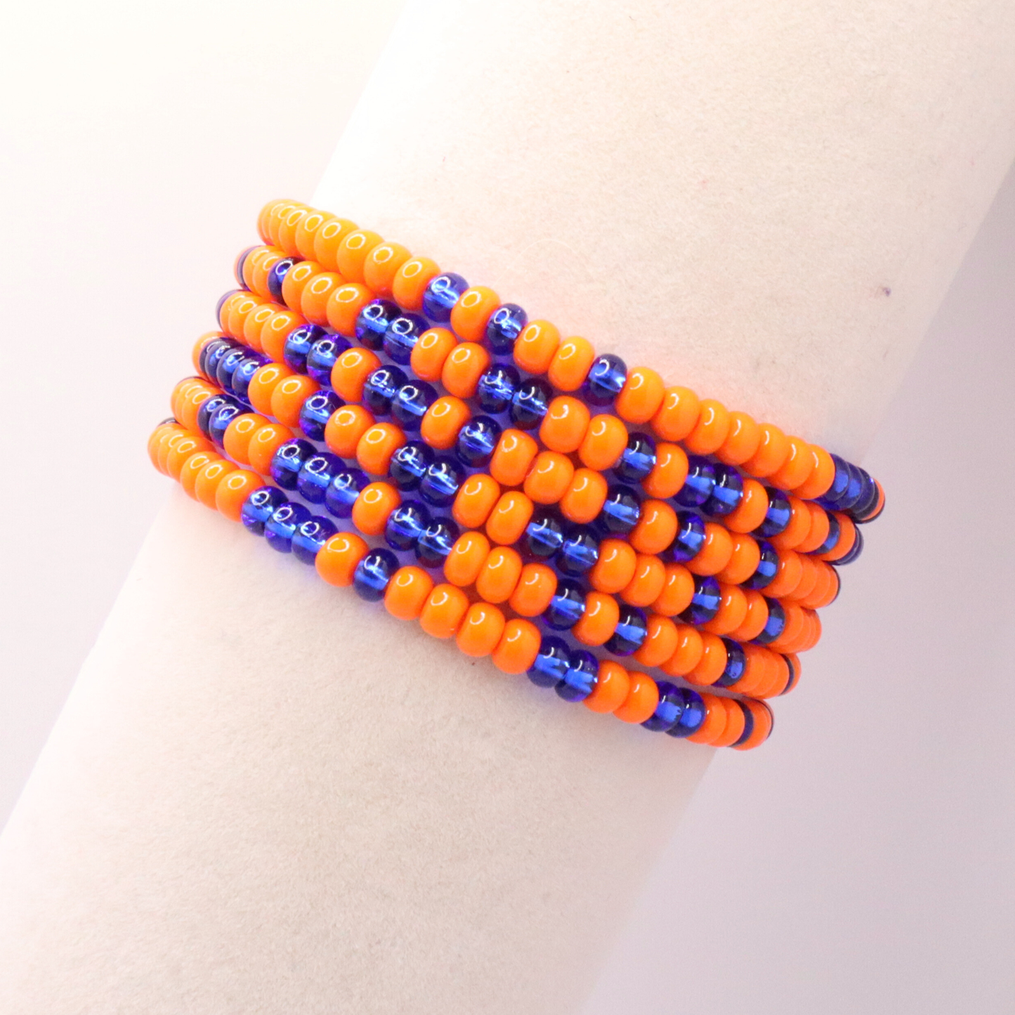 Set of six orange and blue and white seed bead stretch bracelets featuring random orange and blue seed beads on a white background
