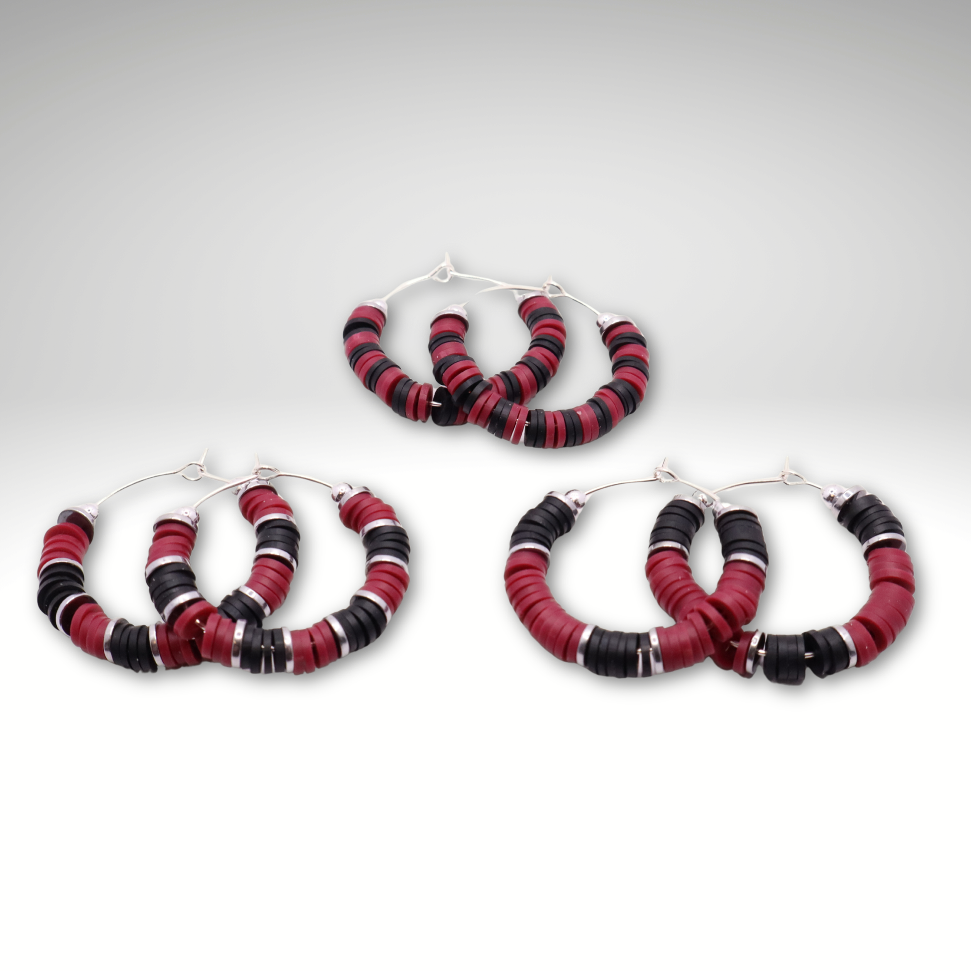 Set of three maroon and black heishi bead hoop earring styles arranged on a white background, showcasing size and pattern variations