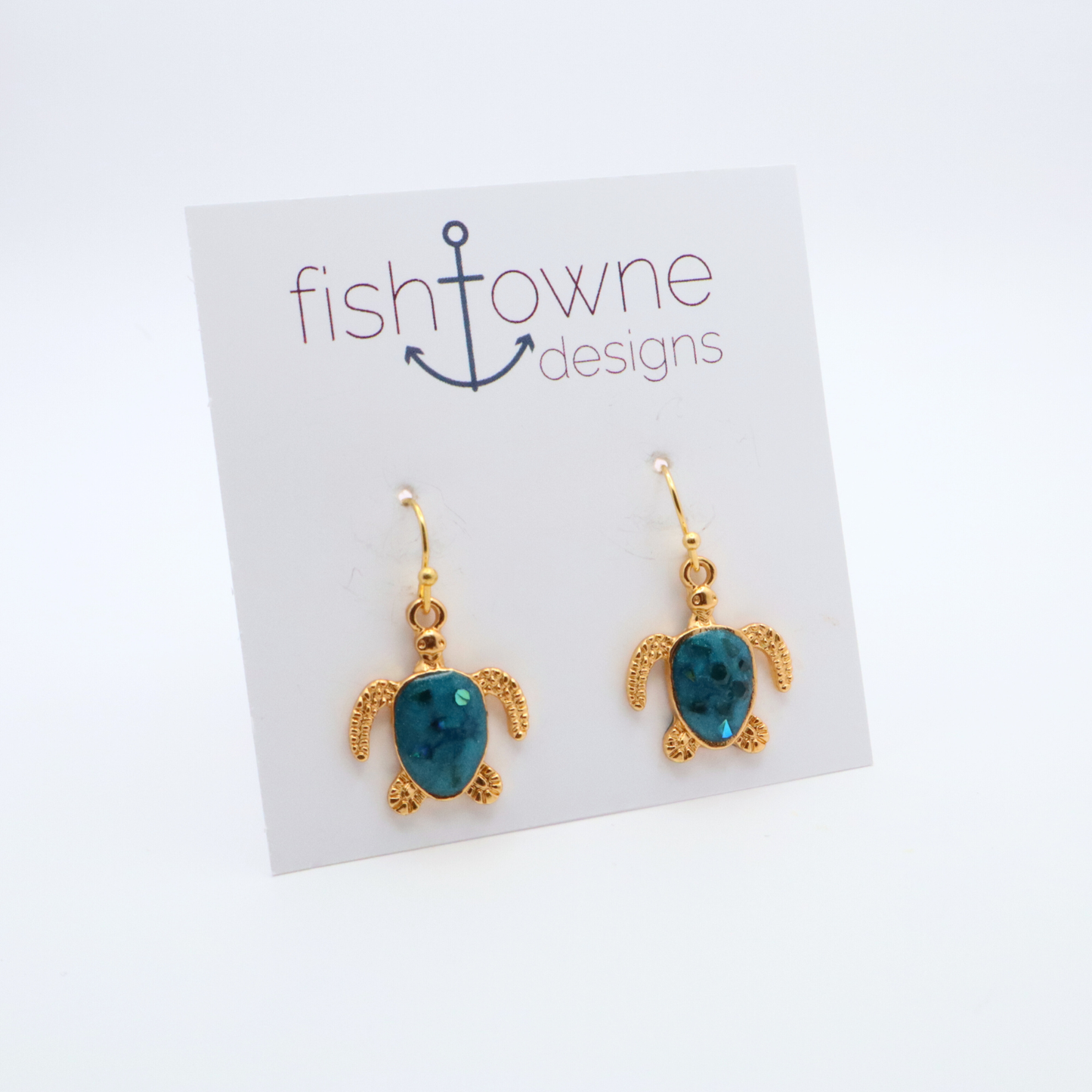 Turtle-shaped gold and teal resin earrings on a Fish Towne Designs card against a white background