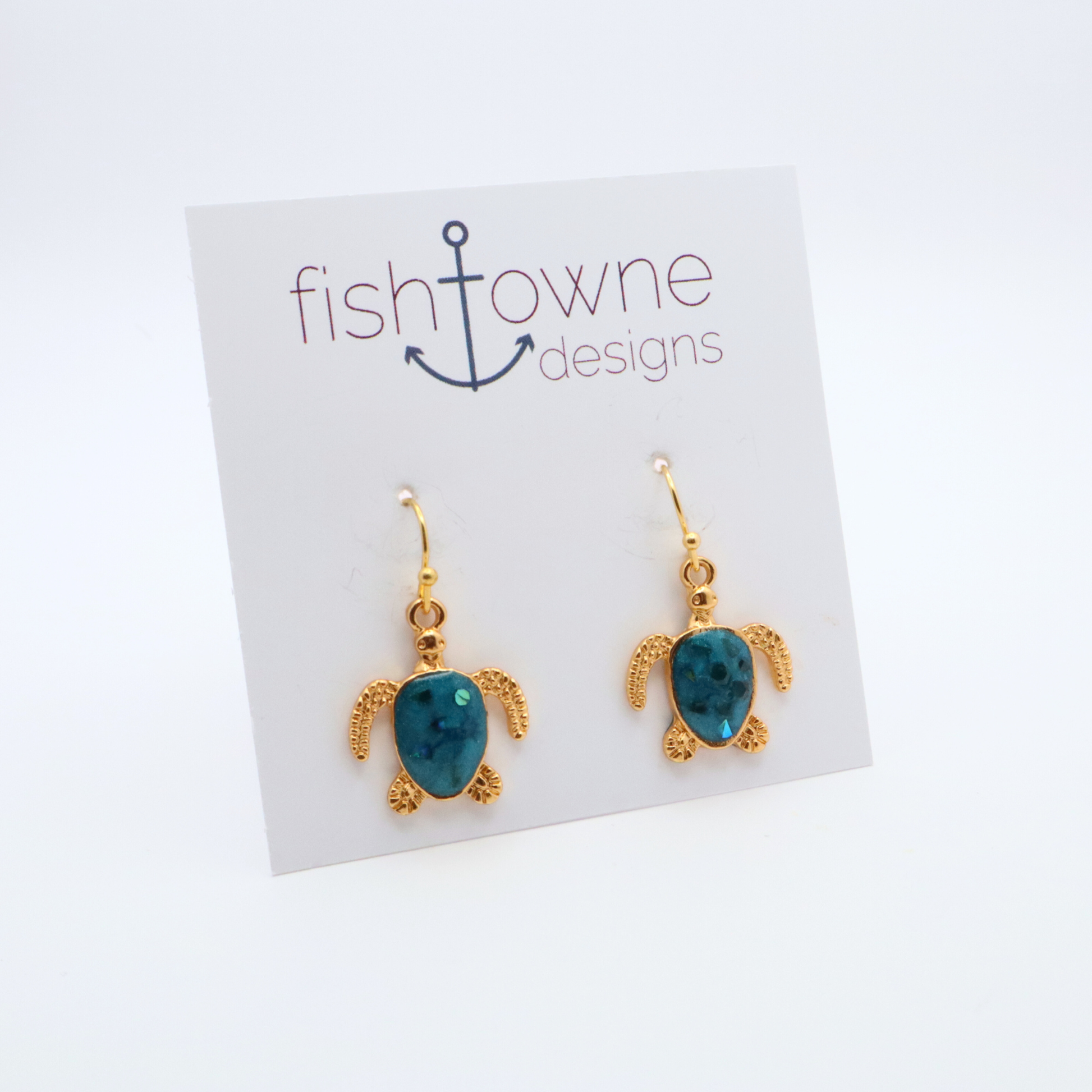 Turtle-shaped gold and teal resin earrings on a Fish Towne Designs card against a white background