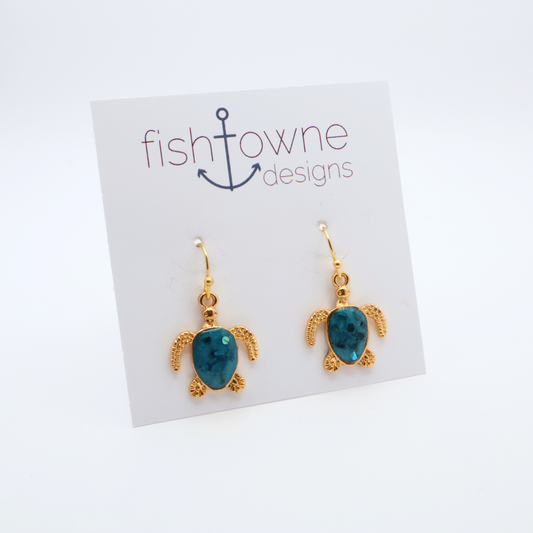 Turtle-shaped gold and teal resin earrings on a Fish Towne Designs card against a white background
