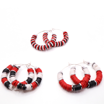 Set of three red, white, and black heishi bead hoop earring styles arranged on a white background, showcasing size and pattern variations