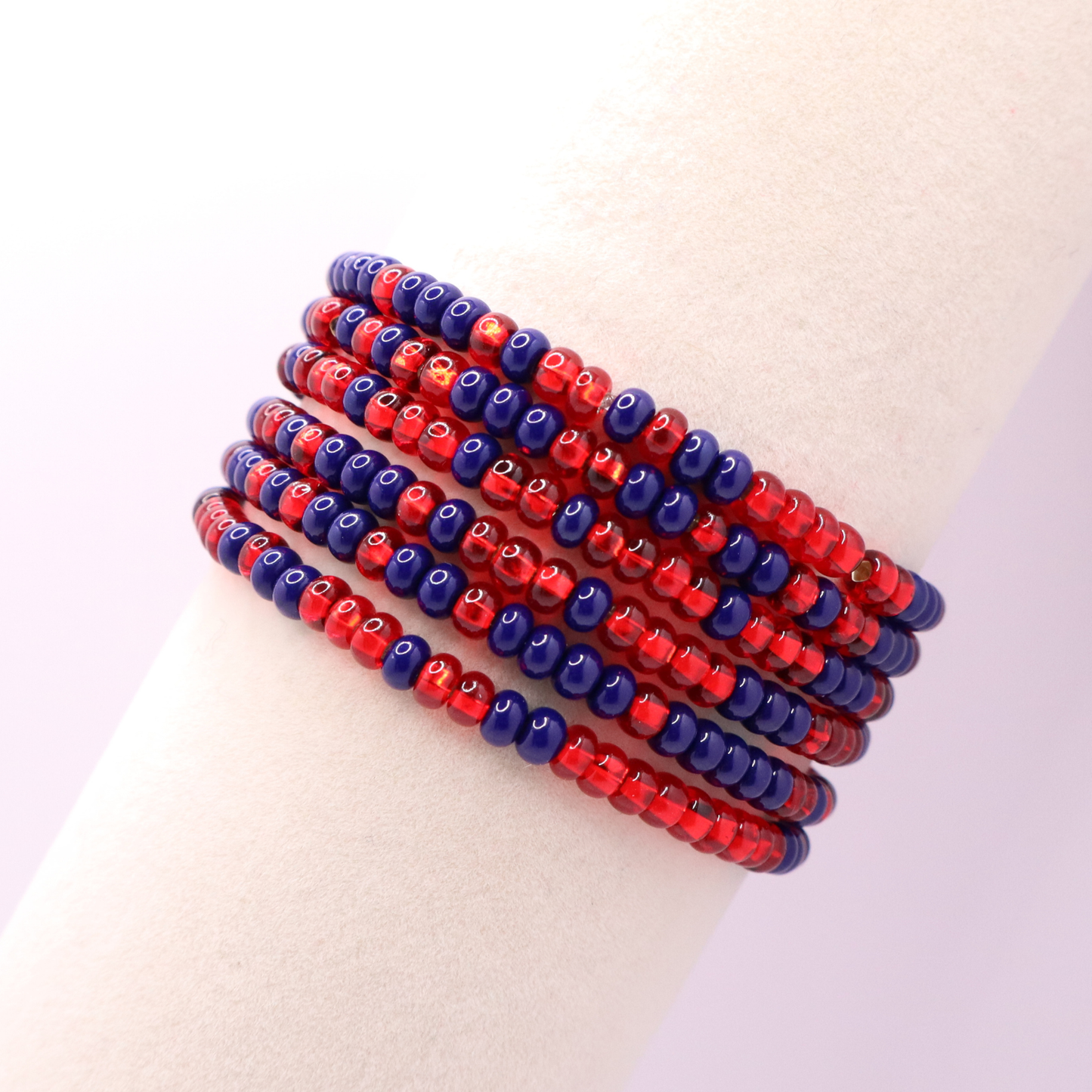 Set of six navy blue and red seed bead stretch bracelets featuring random navy blue and red seed beads on a white background