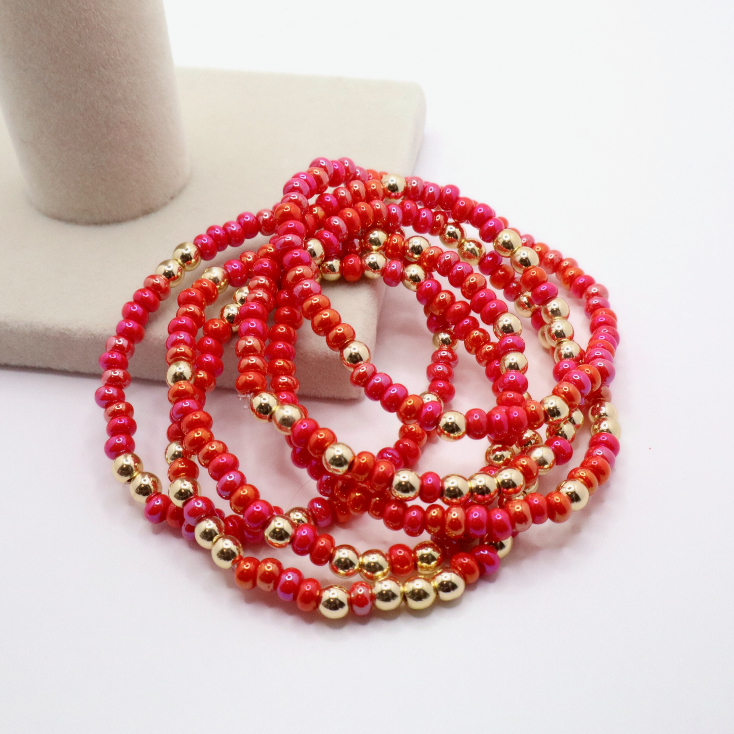 Stack of six pink and gold beaded bracelets on a white surface
