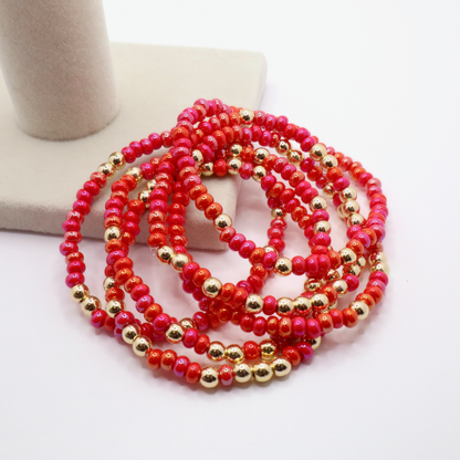 Stack of six pink and gold beaded bracelets on a white surface