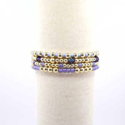 Purple and gold beaded bracelet set featuring crystal accents and coastal-inspired colors.