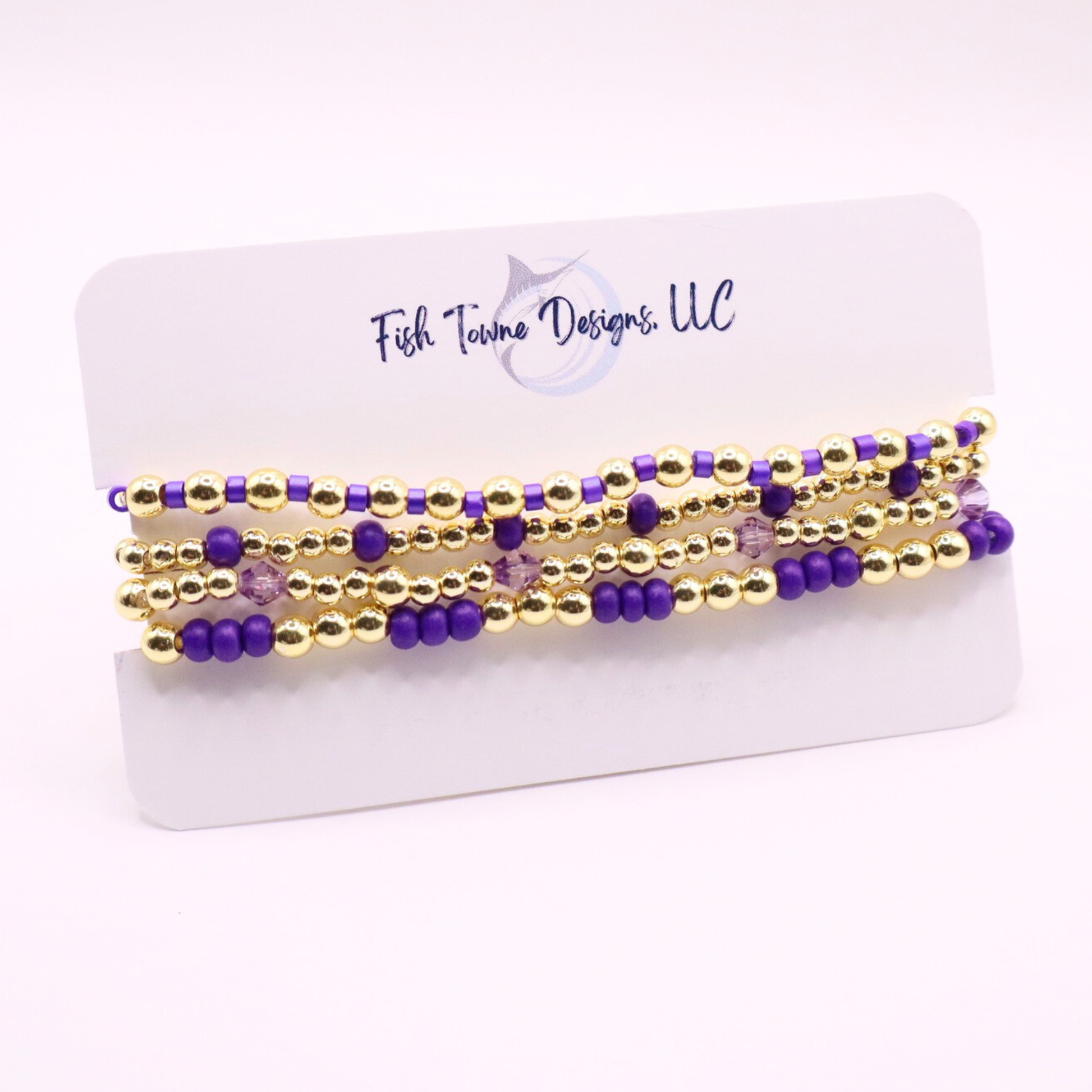 Elegant stack of stretch bracelets featuring rich purple Preciosa seed beads, faceted crystal details, and gold-tone hematite accent beads on a clean white background.