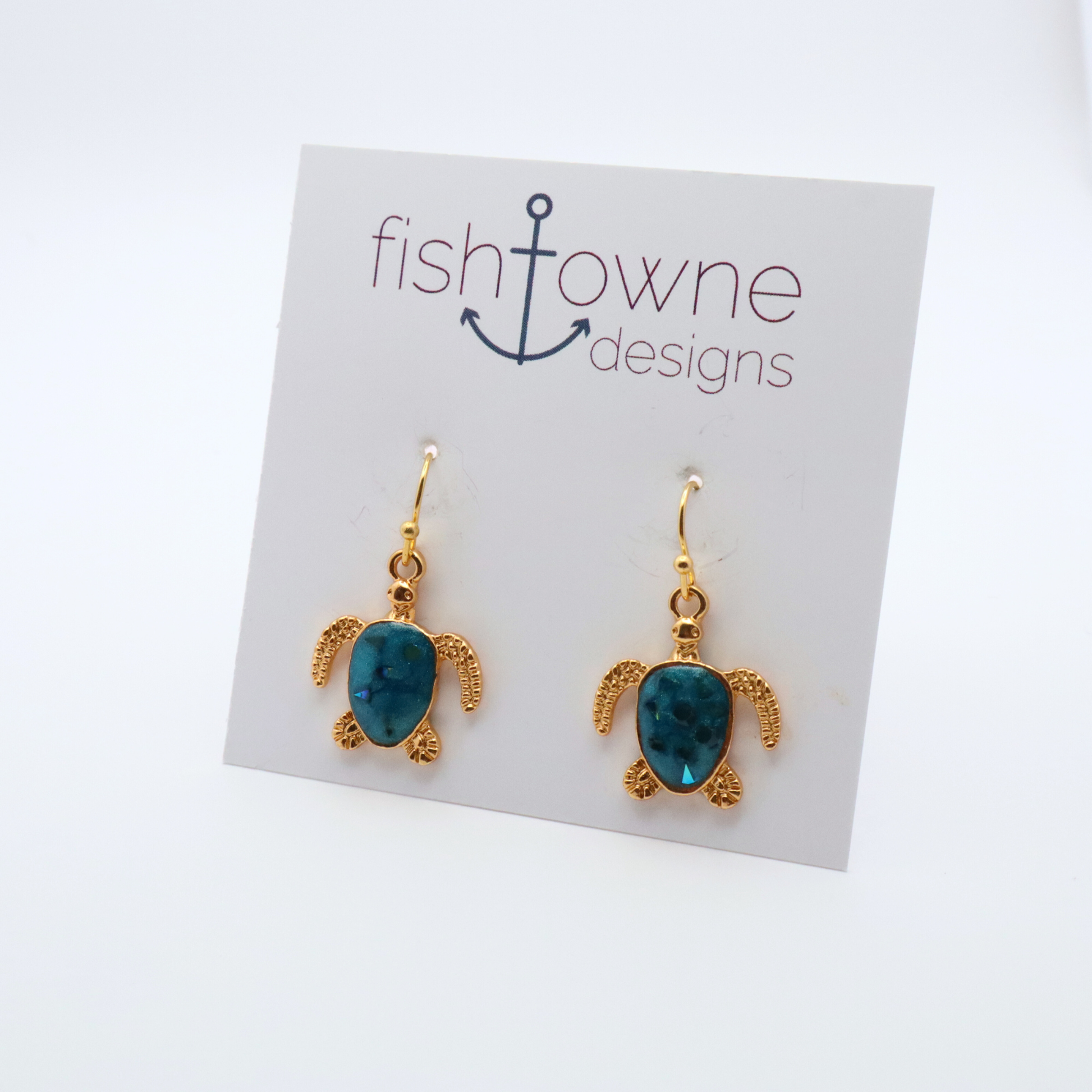 Turtle-shaped earrings with teak blue resin on a Fish Towne Designs display card.