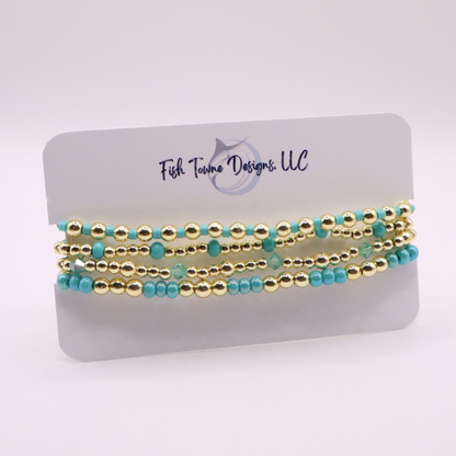 Layered bracelet stack with turquoise Preciosa seed beads, shimmering crystal accents, and gold-tone hematite beads on a clean white background.