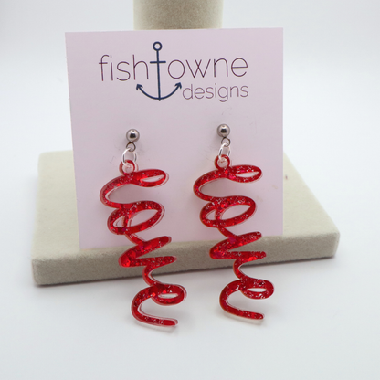 Pink glitter 'love' earrings on a Fish Towne Designs display card