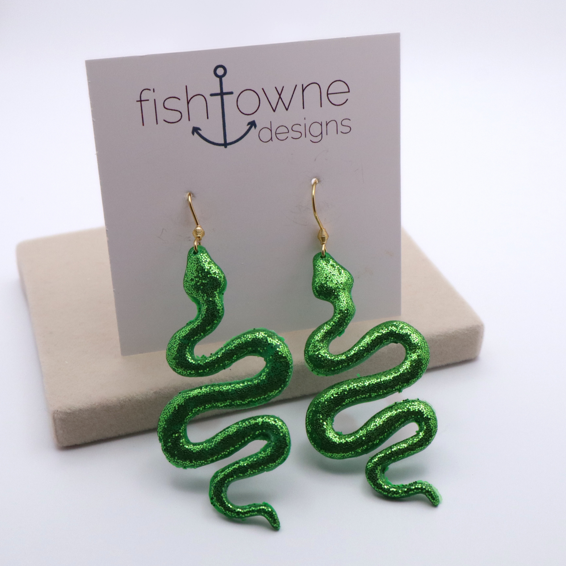 Green snake-shaped earrings on a 'fishtowne designs' card with a beige box.