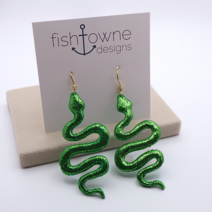 Green snake-shaped earrings on a 'fishtowne designs' card with a beige box.