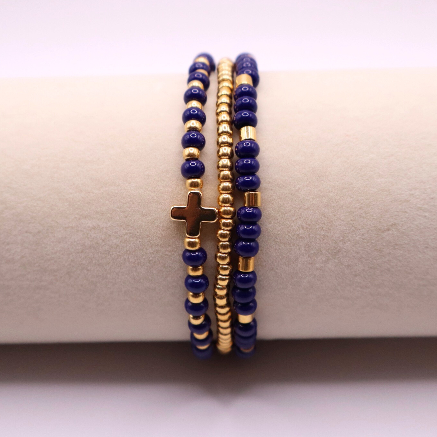 Three beaded bracelets with gold plated and navy blue beads on a beige surface