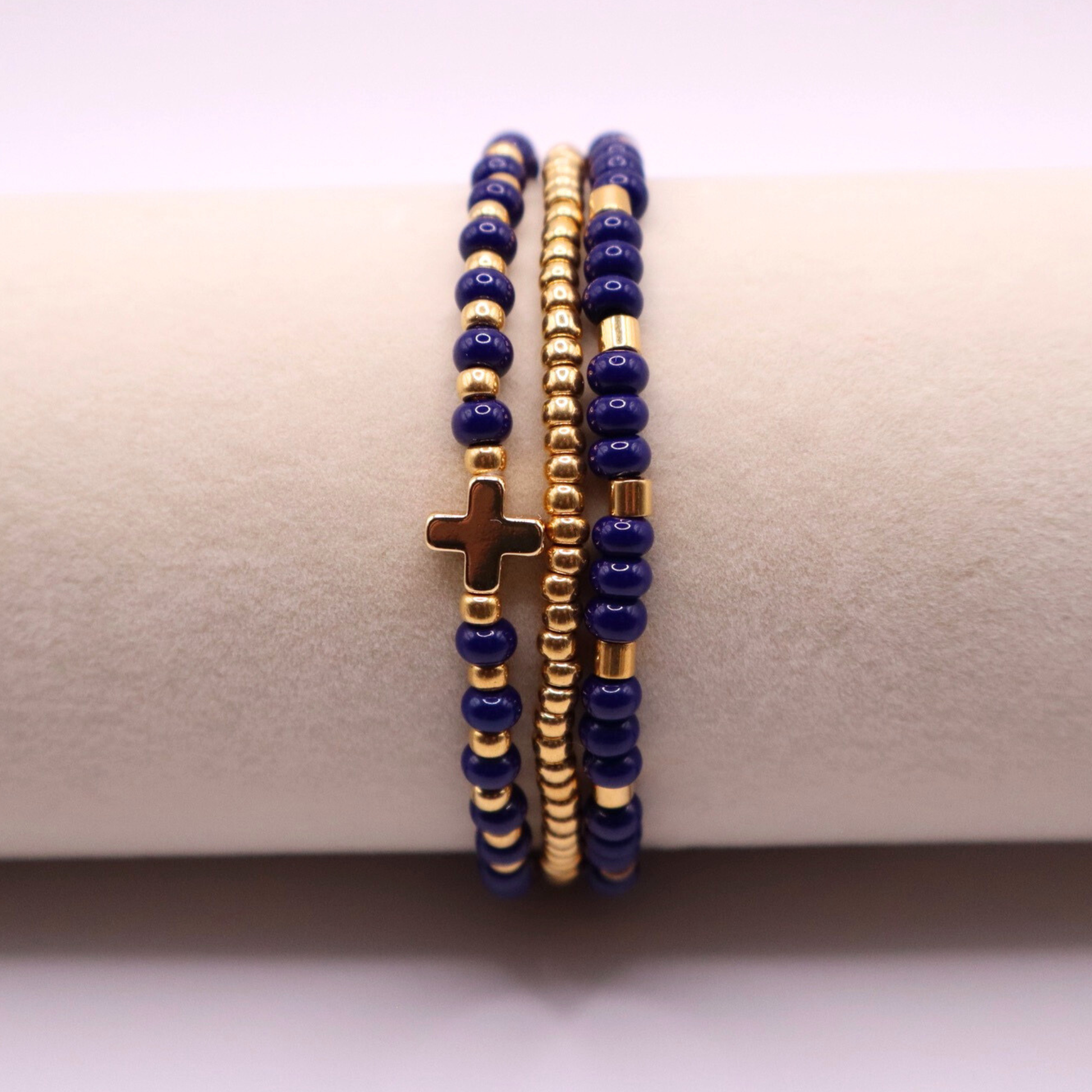 Three beaded bracelets with gold plated and navy blue beads on a beige surface