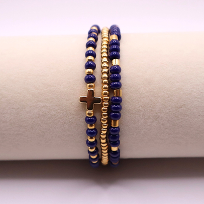 Three beaded bracelets with gold plated and navy blue beads on a beige surface